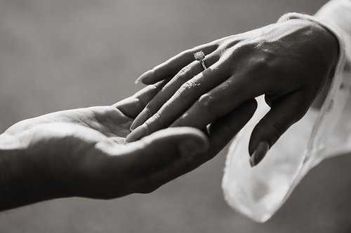 mustavalkoinen kuva vihkiparin käsistä